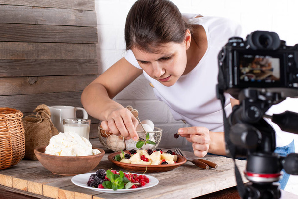 Professionale food blogger scattare foto di pasticceria sul tavolo con fotocamera dslr. Fotografo donna che scatta foto di cibo dolce, macchina fotografica montata su treppiede - Foto, immagini