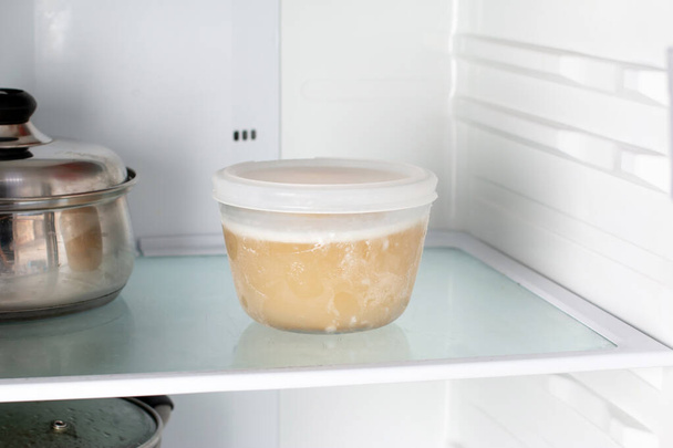 Caldo congelado en un recipiente en el congelador. Alimentos congelados - Foto, imagen