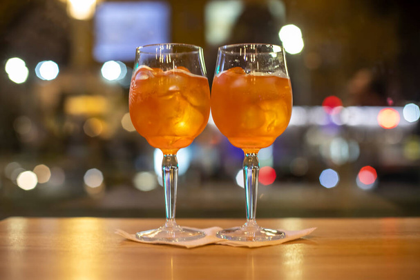 Dos copas de vino con coctel naranja se colocan sobre una mesa de madera en un café.Bebida alcohólica italiana con naranjas y hielo. Primer plano, enfoque selectivo. fiesta - Foto, imagen