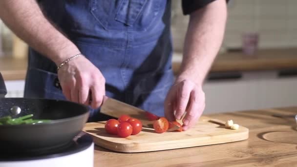 Profesionální kuchař pracuje v kuchyni restaurace. Šéfkuchař nakrájí červené zralé šťavnaté rajče na tenké plátky. Vařím vynikající vitamínový zeleninový salát. koncepce správné výživy doma - Záběry, video