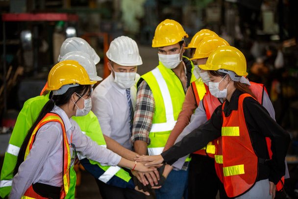 munkavállalók csoportja, a gyárban dolgozók váltása, az emberek sisakot és egyenruhát viselnek egy ipari vállalkozáshoz, a munkavállalók védőmaszkot viselnek a gépipari üzem biztonsága érdekében. - Fotó, kép
