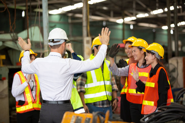 skupina pracovníků, výměna pracovníků v továrně, lidé chodí v přilbách a uniformách pro průmyslový podnik - Fotografie, Obrázek