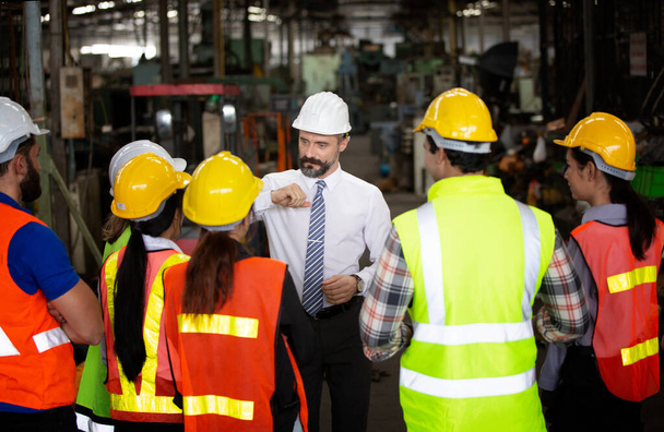 grupo de trabajadores, cambio de trabajadores en la fábrica, personas van en cascos y uniformes para una empresa industrial - Foto, imagen