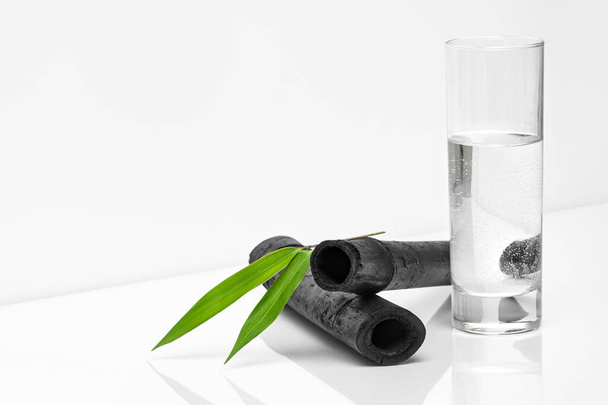 Bâtonnets de filtre à eau en bambou, feuille verte et verre d'eau. Le charbon de bois de bambou naturel est un puissant purificateur qui rafraîchit l'eau du robinet - Photo, image