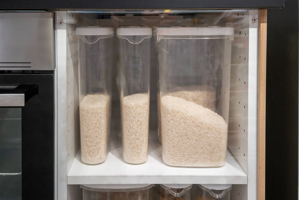 jusmine riz dans les récipients en plastique transparent armoire de cuisine sur étagère blanche. - Photo, image