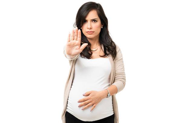 Boze zwangere vrouw die een stopteken toont met haar hand. Verontrustende blanke vrouw voelt zich geïrriteerd en hebben een gevecht met iemand - Foto, afbeelding