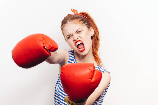 aggressive woman in red wrestling gloves on a light background wide open her mouth cropped view - Foto, Bild