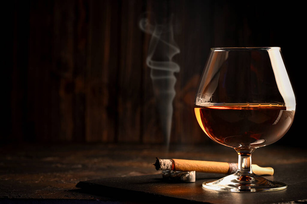 Rum in bicchieri con una bottiglia di rum e un sigaro sullo sfondo. Fondo nero - Foto, immagini