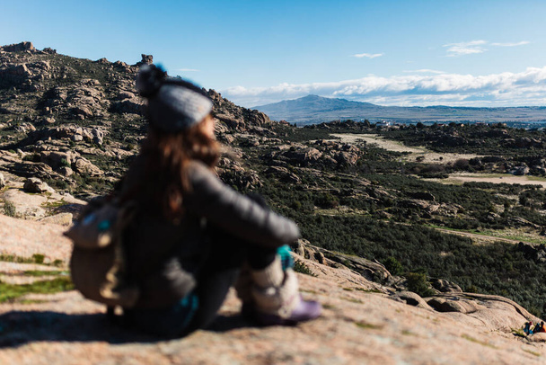 Young active woman with trekking equipment sitting, relaxing and looking at lake and mountains background - Photo, Image