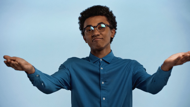 african american teenage boy showing shrug gesture isolated on blue - Foto, afbeelding