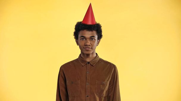 african american teenage boy in party cap isolated on yellow - Фото, зображення