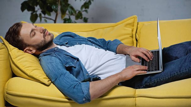 freelancer cansado durmiendo en sofá con portátil - Foto, Imagen