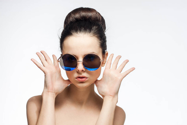 woman wearing sunglasses naked shoulders charm fashion light background - Photo, Image