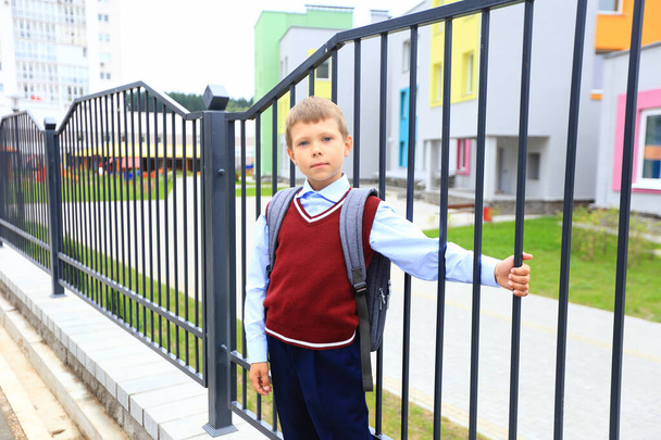 Un chico en uniforme escolar con una mochila en los hombros - Foto, imagen