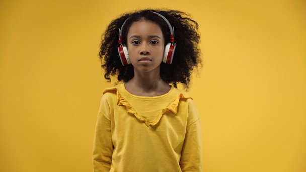 curly african american girl in wireless headphones isolated on yellow - Fotografie, Obrázek