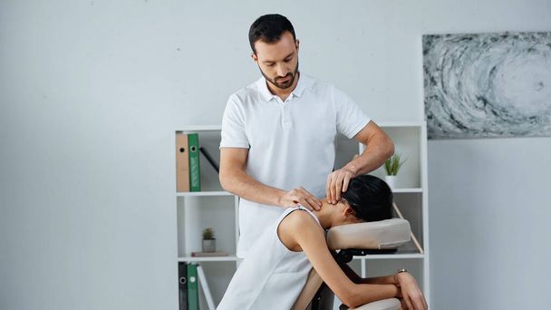 Masseur tut Nackenmassage für Geschäftsfrau auf Massagesessel im Büro  - Foto, Bild