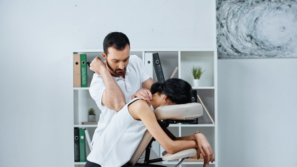 Masseur doing back massage to businesswoman in office  - Φωτογραφία, εικόνα