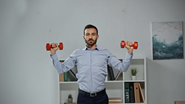 Businessman training with dumbbells in office  - 写真・画像