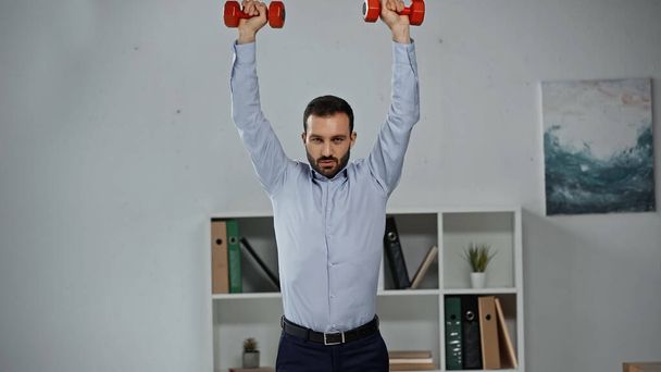 Empresario en entrenamiento formal con pesas en oficina  - Foto, Imagen