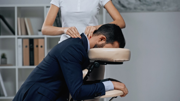 massagista fazendo massagem no pescoço para homem de negócios em terno no escritório  - Foto, Imagem