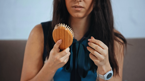 vista recortada de mujer molesta sosteniendo cepillo de pelo  - Foto, imagen