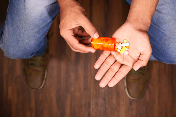 Männerhand mit Medikament aus Pillenbehälter verschüttet  - Foto, Bild