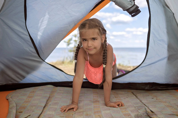 野生の森の中のビーチのキャンプ場でテントを見ている子供、アクティブな夏、地元の探索 - 写真・画像