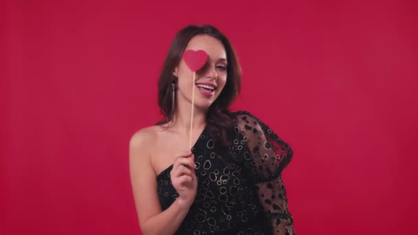 fröhliche Frau in schwarzem Kleid mit Herz auf rotem Stock - Filmmaterial, Video