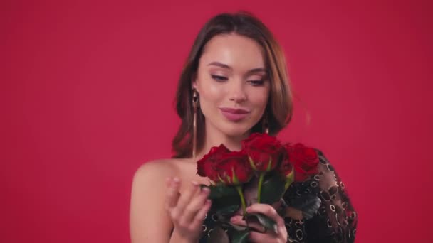 mulher alegre no vestido segurando rosas isoladas no vermelho - Filmagem, Vídeo