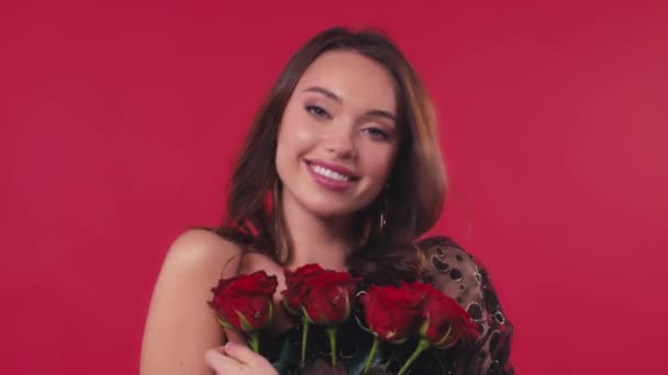 χαρούμενη γυναίκα με φόρεμα κρατώντας τριαντάφυλλα απομονωμένα στο κόκκινο - Πλάνα, βίντεο