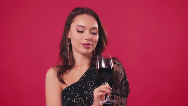 szczęśliwa kobieta wąchająca wino w szklance odizolowanej na czerwono - Materiał filmowy, wideo