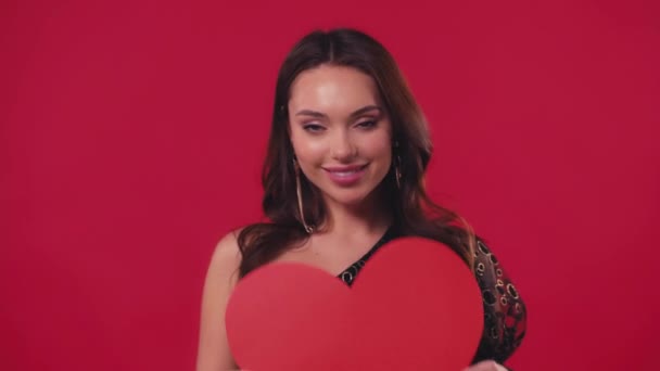 mujer feliz sosteniendo corazón de cartón aislado en rojo - Imágenes, Vídeo