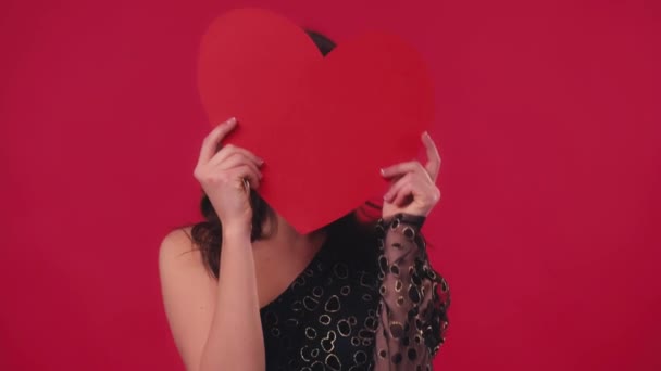 onnellinen nainen peittää kasvot paperilla sydän eristetty punainen - Materiaali, video