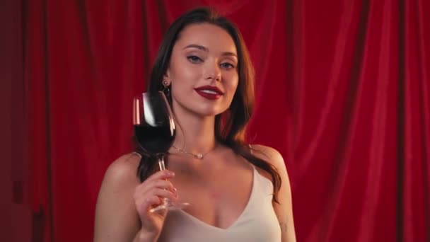 donna felice che tiene il bicchiere e beve vino sul rosso - Filmati, video