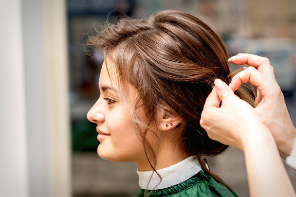 side view of hands of hair stylista stylizacja włosy pięknej młodej białej brunetki kobieta w salonie piękności - Zdjęcie, obraz