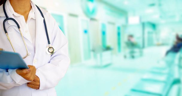 Medicine doctor with uniform stethoscope in hand .The background is a blur of the hospital.There is golden light of the morning shone through the window, looking warm.Healthcare and medical concept. - Photo, Image