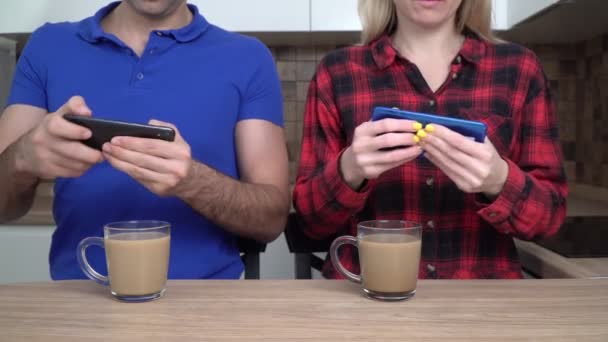 Nuori pari mies ja nainen pelata tietokonetta mobiili videopelejä yhdessä älypuhelimilla - Materiaali, video