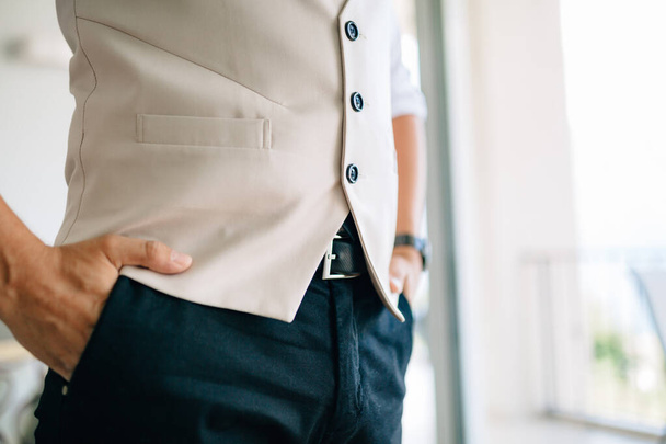 Мужчина, держащий руки в карманах брюк в гостиничном номере во время подготовки к свадебной церемонии  - Фото, изображение