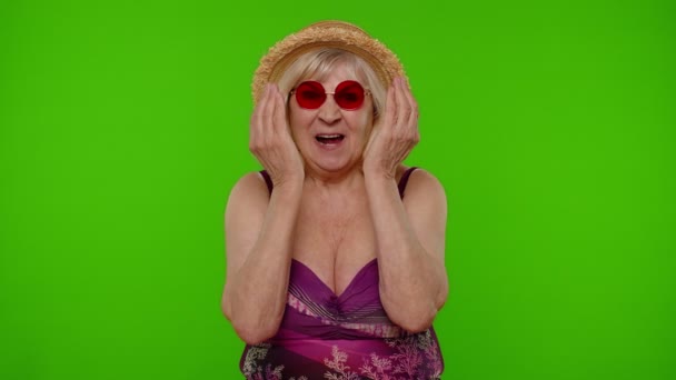 Αστεία διασκεδαστική ηλικιωμένη τουρίστρια με μαγιό, χαζολογάει κάνοντας ηλίθια, άμυαλη έκφραση. - Πλάνα, βίντεο