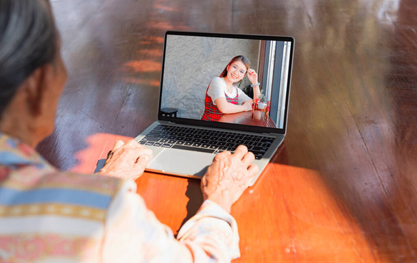 Back view of old woman talking video calling on computer with smiling daughter Elderly woman communicating online using laptop webcam chat with children Happy home quarantine. - Photo, Image