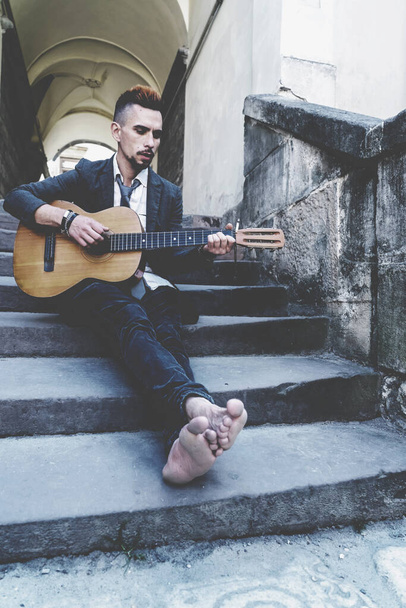 Männlicher Straßenmusiker spielt mit nackten Füßen im Freien in der alten europäischen Stadt.  - Foto, Bild