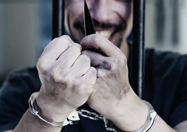 犯罪のために投獄されたタバコを吸う動揺した手錠をかけられた男は、深刻な悪役のために処罰されました。閉めろ。水平像. - 写真・画像