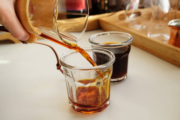 свежеваренный черный налить на кофе наливают в два стакана. альтернативное ручное разливание по дрип-пивоварению, специальность - Фото, изображение