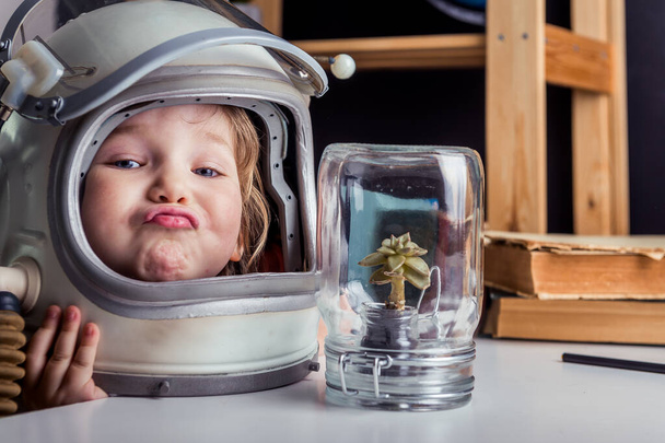 Vtipné dítě v kosmonautské helmě s rostlinou ve sklenici. Věda pro děti a vzdělávání ve škole - Fotografie, Obrázek