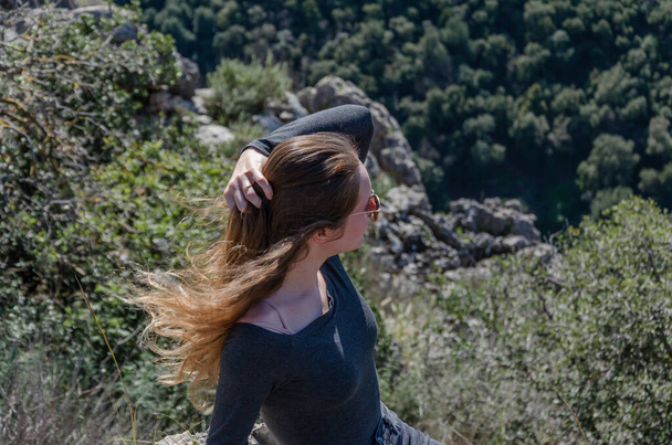 Молодая модель девушка с длинными волосами позирует перед камерой в горах на скалах - Фото, изображение