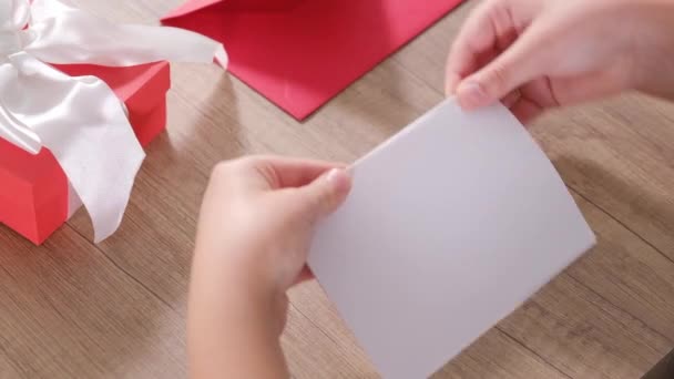The happy boy prepares greeting card with inscription I love you and gift for Mother's Day or Birthday. - Footage, Video