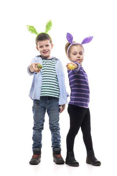Cool proud little boy and girl children with bunny ears showing painted Easter eggs at camera. Full body isolated on white background.  - Photo, Image
