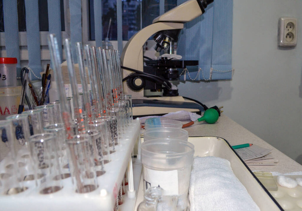 Mikroskobun arka planındaki kan ve idrar tahlilleri için tıbbi test tüpleri özellikle bulanık.. - Fotoğraf, Görsel