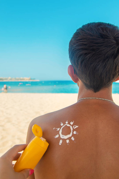 Дівчина на пляжі наносить сонцезахисний крем на шкіру чоловіка. Вибірковий фокус. природа
. - Фото, зображення