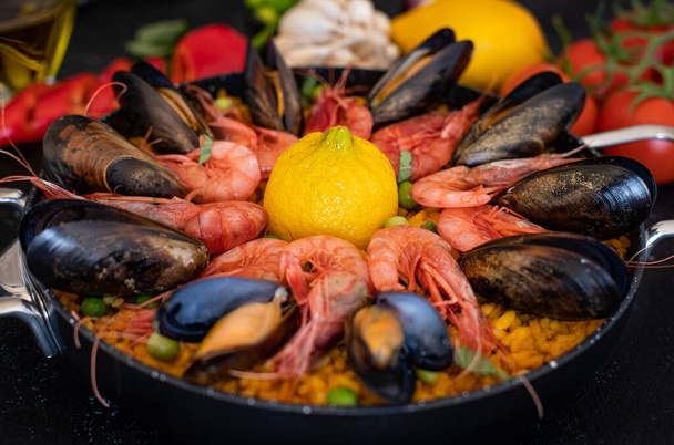traditionelle Paella mit Meeresfrüchten auf dem Tisch. Spaniens Nationalgericht Paella mit Garnelen, Tintenfischen, Venusmuscheln und Muscheln. - Foto, Bild